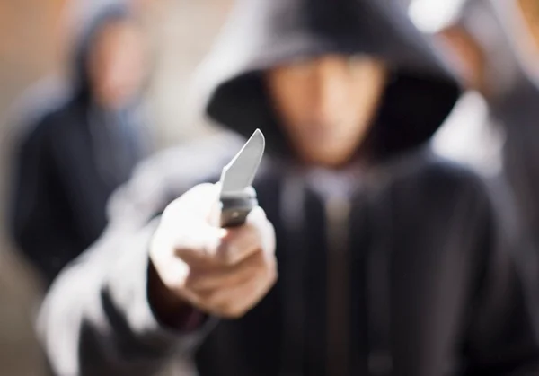 Pessoa encapuzada segurando faca em uma das mãos- Metrópoles