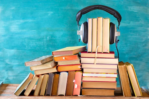 Imagem mostra livros empilhados e fones de ouvido - Metrópoles