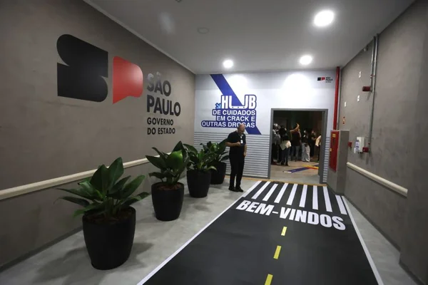 Interior do hub de cuidados para dependentes químicos na região da Cracolândia, em SP, com placas com o nome do local, logotipo do governo do estado e uma saudação: "Bem-vindos"