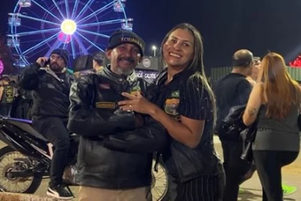 Imagem colorida mostra casal abraçado vestido de preto