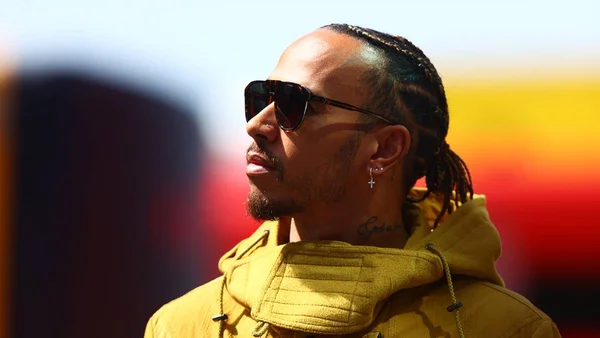 Lewis Hamilton usa casaco amarelo e óculos escuro