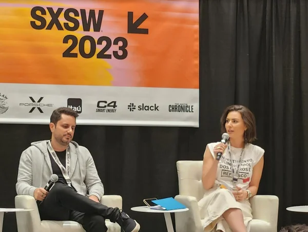 Imagem colorida da SxSW mostra João Pedro Resende, CEO do Hotmart, e Nathalia Arcuri, fundadora do canal "Me Poupe palestrando