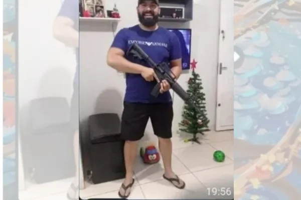 Print de grupo foto com homem segurando fuzil - Metrópoles