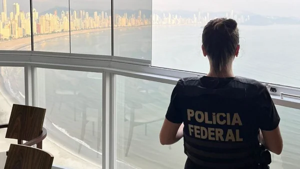 Foto colorida de agente da PF olhando vista do apartamento - Metrópoles