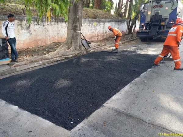 imagem colorida mostra rua com operários trabalhando no reparo de parte do piso com asfalto novo - Metrópoles