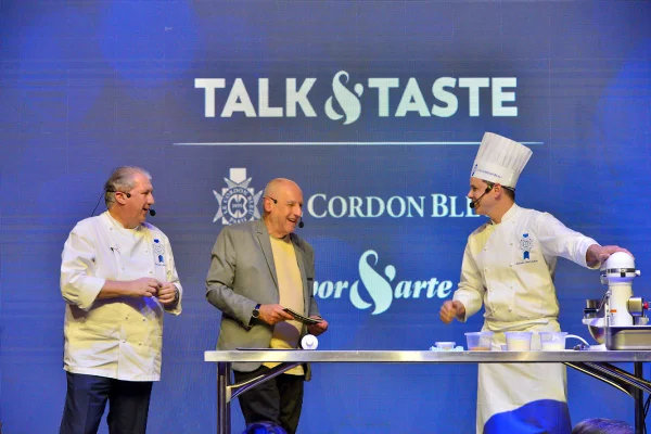 na foto temos tres chefs em um palco