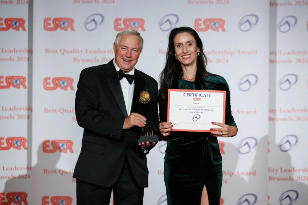 Fotografia colorida mostrando homem e mulher em premiação segurando certificado e troféu-Metrópoles