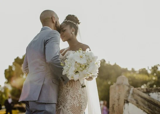 Foto colorida de IZA e Sérgio Santos no casamento, cantora usa vestido de noiva e ele, terno - Metrópoles