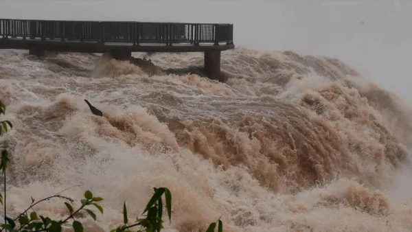 Foto mostra cheia nas Cataratas do Iguaçu, na fronteira entre o Paraná e a Argentina, com fortes ondas de água de coloração amarronzada - Metrópoles