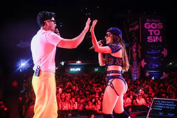 Imagem colorida de Anitta e Léo Foguete cantando juntos no Ensaios da Anitta - Metrópoles