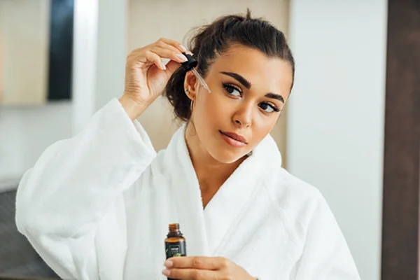 Foto de uma mulher hidratando a pele do rosto