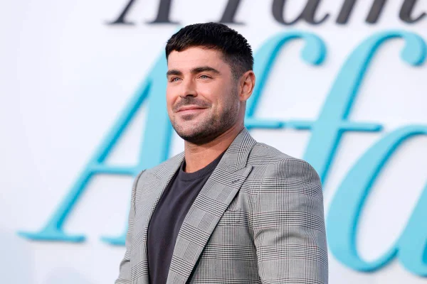 Na imagem colorida, Zac Efron aparece de terno cinza em tapete vermelho - Metrópoles