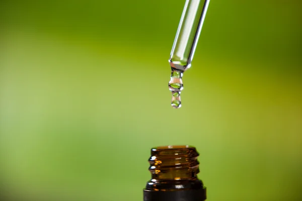 Gota de óleo pingando da pipeta para dentro do frasco de óleo essencial. Melatonina em gotas. Metrópoles