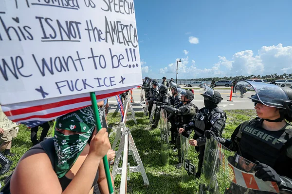 WEST PALM BEACH, FLÓRIDA - 14 DE JUNHO: (NOTA DO EDITOR: A imagem contém palavrões.) Policiais do xerife de Palm Beach impedem manifestantes de atravessar uma ponte em direção à casa do presidente Donald Trump em Mar-a-Lago durante o protesto "No Kings Day" (Dia Sem Reis), em 14 de junho de 2025, em West Palm Beach, Flórida. Centenas de marchas e protestos contra o governo Trump estão acontecendo nos Estados Unidos hoje, em oposição ao desfile militar que celebra o 250º aniversário do Exército dos EUA, que acontece em Washington, D.C., coincidindo com o aniversário do presidente Trump. (Foto de Joe Raedle/Getty Images)