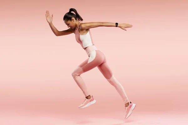 Foto colorida de uma mulher vestida de rosa que se prepara para correr - Metrópoles
