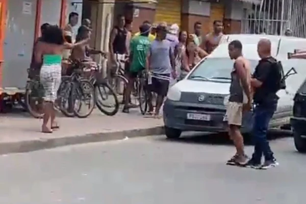 Imagem colorida de policial prendendo homem em meio a multidão - Metrópoles