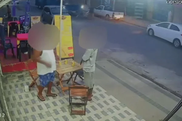 Imagem colorida de dois homens em uma calçada vendo um ônibus azul atropelando um jovem de bicicleta - Metrópoles