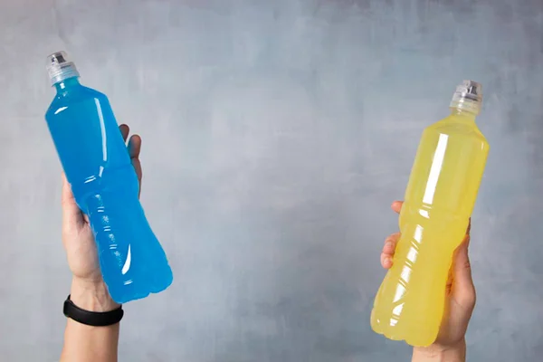 Imagem colorida: duas garrafas de isotônicos azul e amarelo - Metrópoles