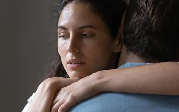 Mulher abraçando homem com olhar desconfiado