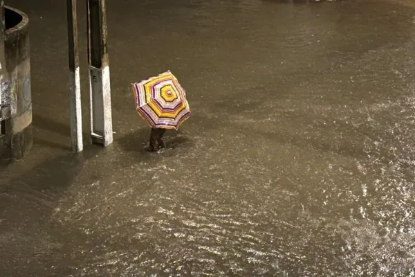 Imagem colorida de pessoa andando em local alagado devido as fortes chuvas em Maceió - Metrópoles