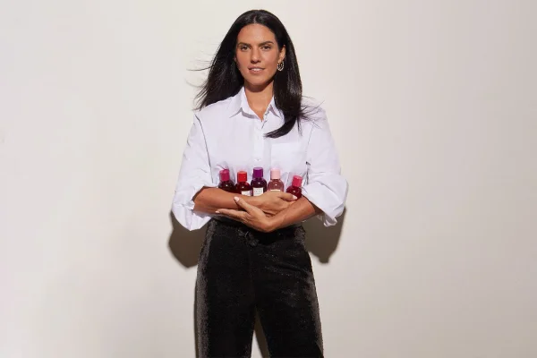 Mulher com camisa branca segurado frascos de perfume