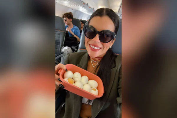 Imagem colorida mostra a influenciadora Rosana Ferreira segurando uma marmita com ovos dentro de um avião - Metrópoles