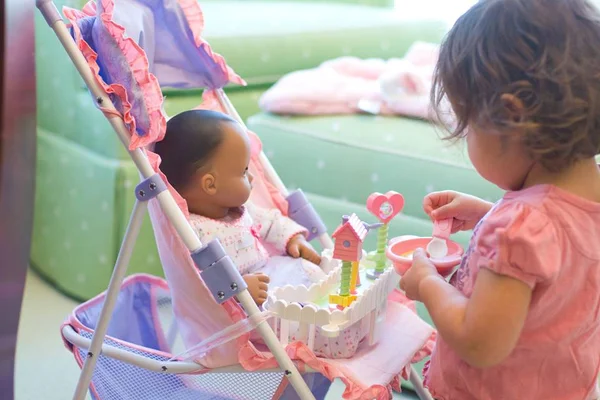 Criança dando comida para boneca no carrinho - Metrópoles