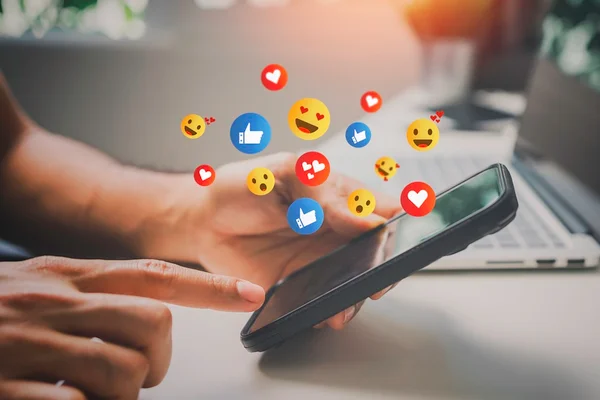 Foto colorida. Emojis em frente a tela de celular