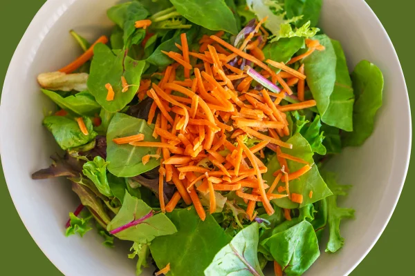 Imagem mostra salada de folhas verdes com cenoura ralada - Metrópoles