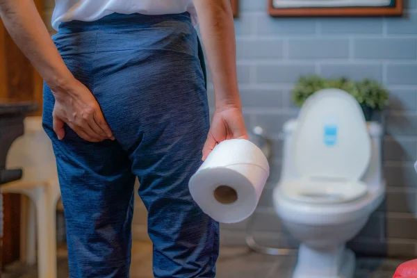 homem no banheiro segurando papel higiênico