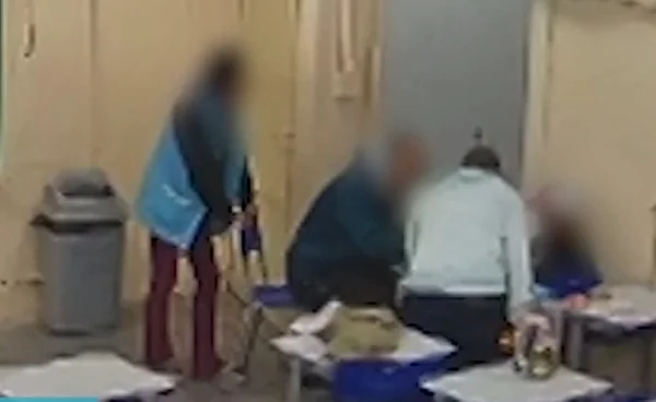 foto colorida mostra dois professores de pé cercando aluno sentado em sala de aula; uma terceira professora observa a distância - Metrópoles