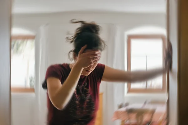 Mulher jovem apoiada na parede com mão na cabeça - AVC pode começar com sintomas leves. Saiba quais sinais exigem atenção - Metrópoles