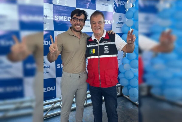 Dois homens em pé abraçados e fazendo o símbolo da paz com as mãos