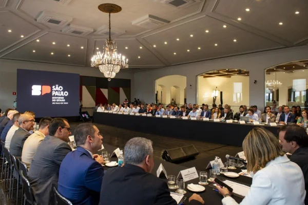 Imagens coloridas mostram reunião entre governador paulista e prefeitos de várias cidades, todos sentados à mesa
