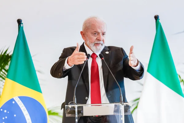 Imagem colorida do presidente Lula, com bandeiras do Brasil e Itália ao fundo - Metrópoles