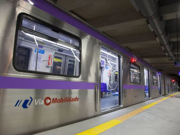 Imagem colorida mostra trem prateado, com faixa lilás, sob as janelas do metrô de São Paulo - Metrópoles