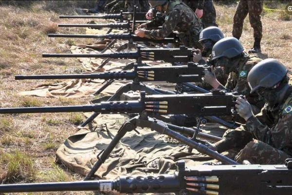Militares com roupa camuflada lado a lado segurando metralhadoras antiaérea - Metrópoles