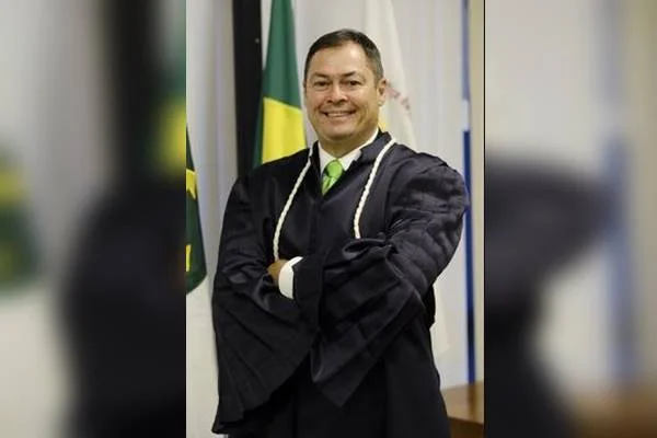 Fotografia colorida de homem vestido de toga com os braços cruzados