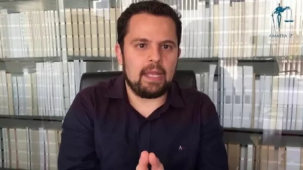 homem falando com biblioteca atrás
