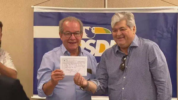 a foto mostra josé aníbal e datena posando com a ficha de filiação do apresentador nas mãos