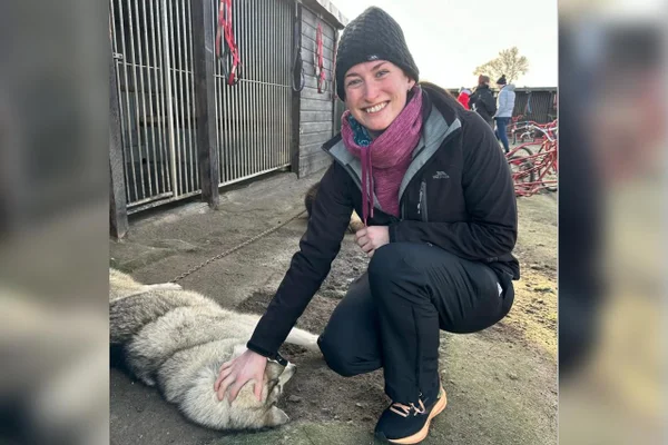Foto da personagem Julie Brinklow agachada fazendo carinho em um cachorro. Ela teve cancer de mama. Metrópoles