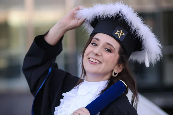 Foto colorida de jovem com beca de formatura - Metrópoles