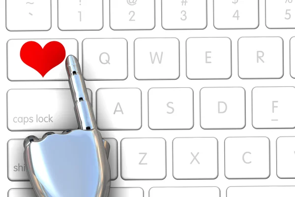 Ilustração de um techado de computador branco, com um braço robótico apertando uma tecla com um coração vermelho - Metrópoles.