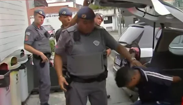 Imagem colorida mostra policial militar (PM) tirando um homem de dentro de uma viatura. Ele foi um dos ladrões presos dentro de um shopping na zona leste de São Paulo após entrar no local para fugir dos policiais, que o perseguiam por ele integrar uma quadrilha que fazia arrastões na região - Metrópoles