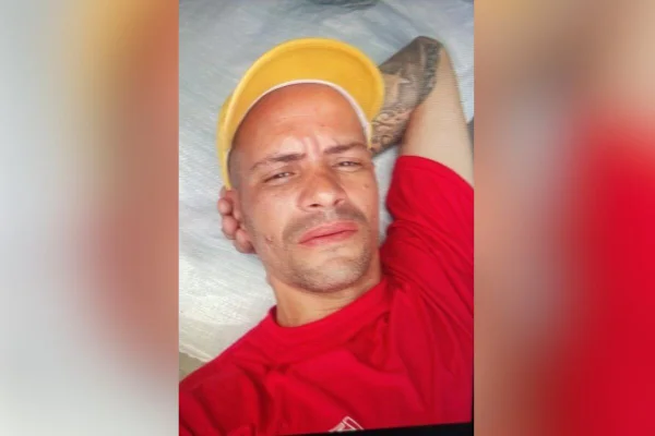 Foto colorida de homem de boné amarelo, com cabeça apoiada no antebraço esquerdo - Metrópoles