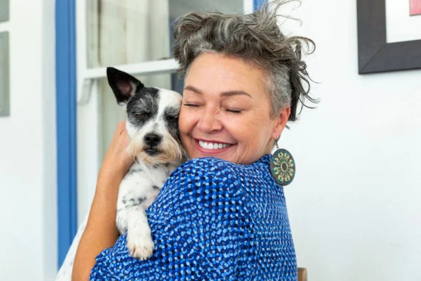 Imagem colorida de mulher abraçando cachorro