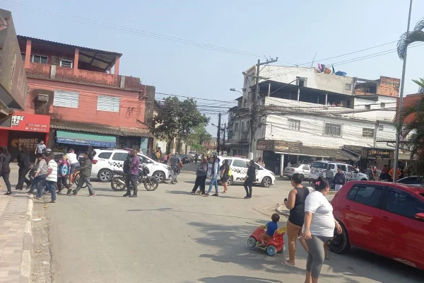 Pessoas caminham entre viaturas da PM