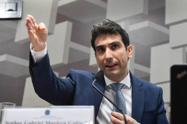 Imagem de Gabriel Galípolo, presidente do Banco Central, vestindo terno azul escuro e camisa clara, com gravata azul clara, e gesticulando - Metrópoles