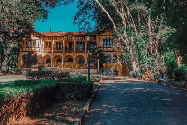 Imagem colorida de um parque arborizado com uma casa ao fundo - Metrópoles