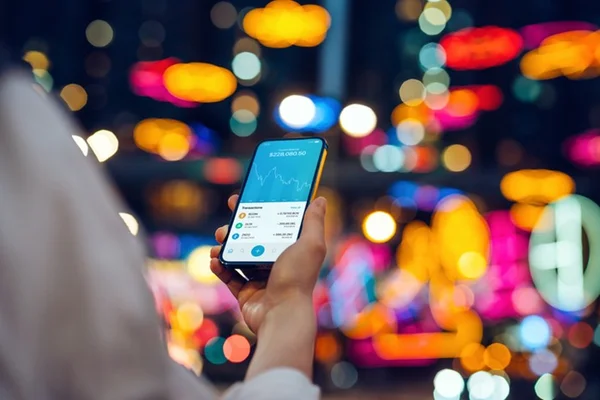 Pessoa branca olhando celular na rua e usando aplicativo de criptomoedas - Metrópoles